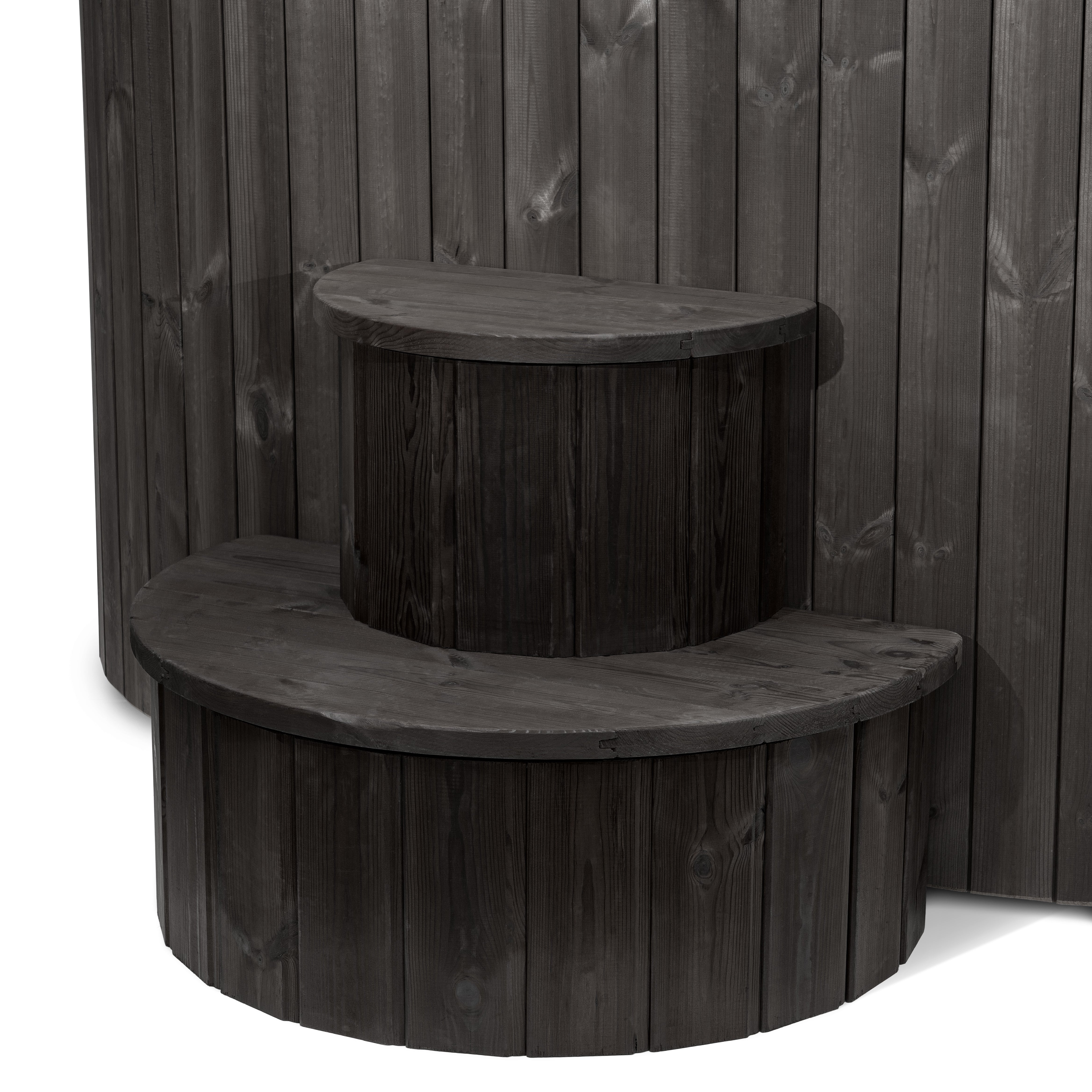 A wooden step or platform with a curved top, situated against a wooden wall.