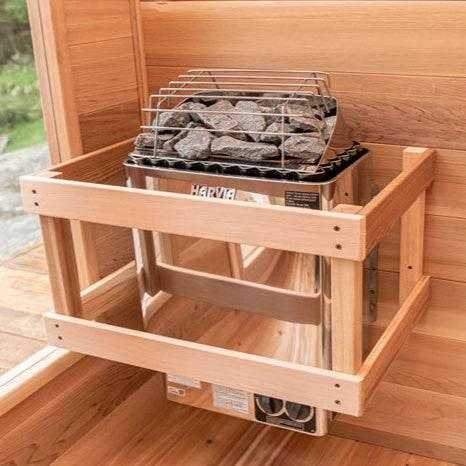 Harvia KIP Electric Sauna Heater with a dark metal body, exposed sauna stones, and protective wooden safety rails
