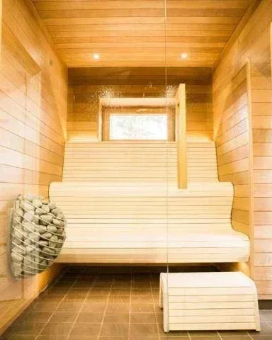 HUUM DROP 9kW Electric Sauna Heater in a silver metal basket filled with pale stones, mounted on a wooden sauna wall