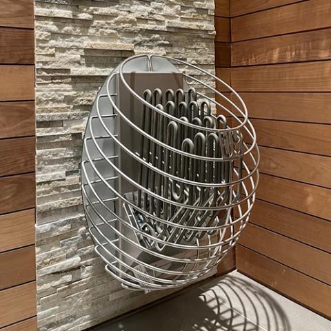 HUUM DROP wall mounted electric sauna heater in cedar interior with rounded stone basket, interior side wall view