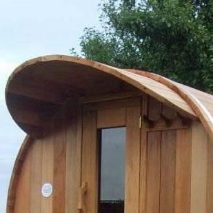 Leisurecraft Overhang Cove Kit in natural cedar, with a curved wooden roof extension above a sauna doorway