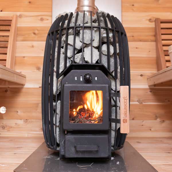 Leisurecraft Timberglow wood-burning sauna heater with visible firebox and surrounding stones inside cedar sauna