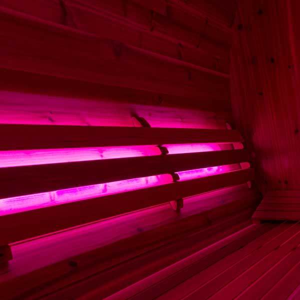 Red-lit sauna backrest installed against cedar sauna wall for vibrant nighttime ambiance