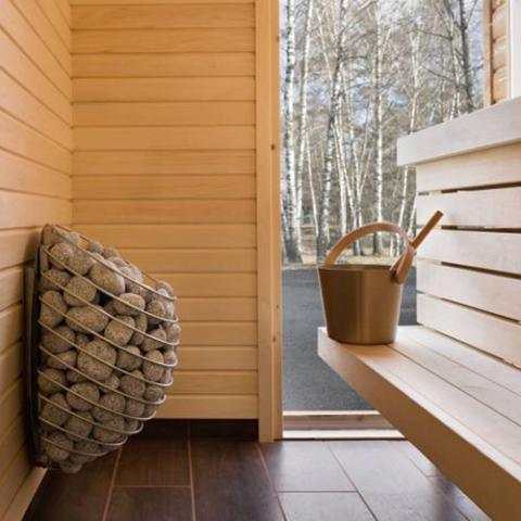 HUUM DROP 4.5kW Electric Sauna Heater with a rounded basket packed with sauna stones and a dark metal frame