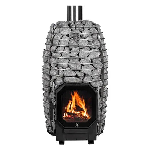HUUM Hive Flow Wood-Burning Heater with a black firebox, burning flames, and a tall cylindrical steel cage filled with gray stones