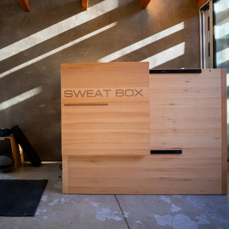 Sweat Box Infrared Sauna in a modern home gym. Compact, energy-efficient sauna with infrared heat panels and red light therapy for wellness and recovery