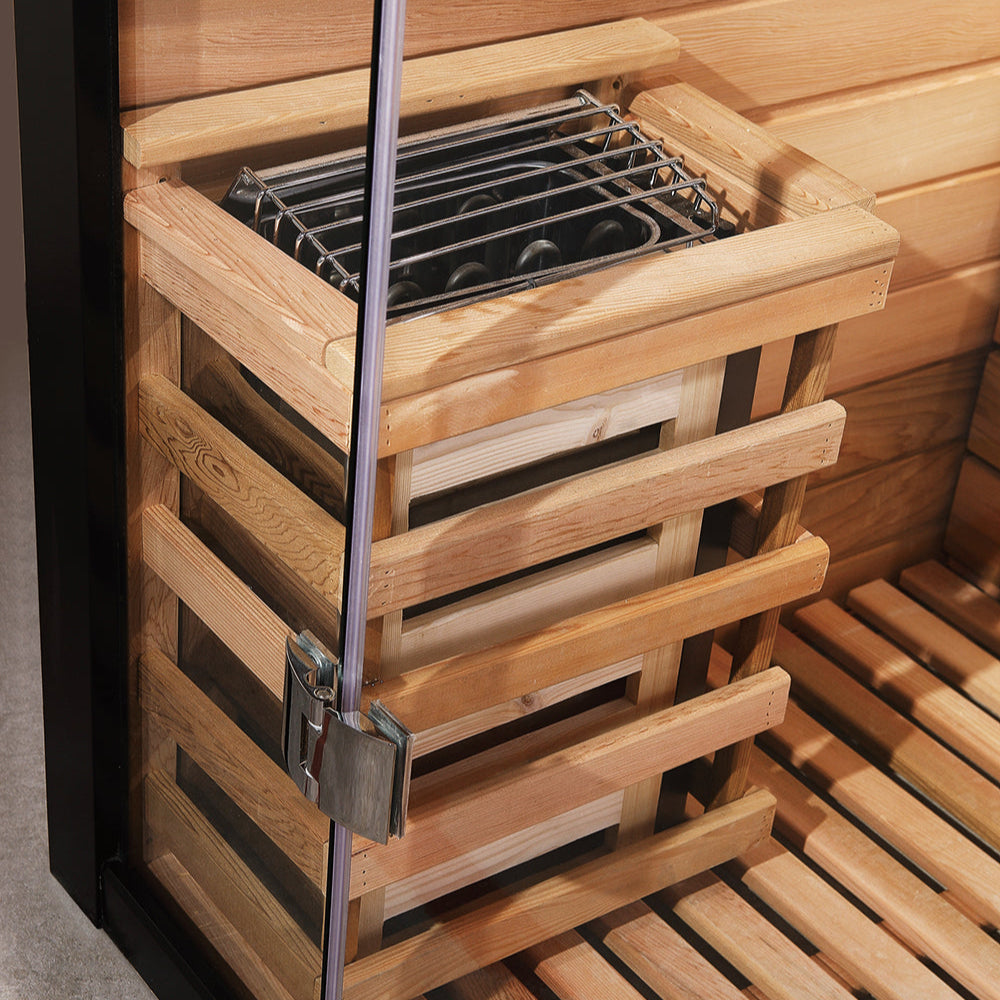 Interior of Waja sauna showing electric heater with wooden safety guard and open glass door
